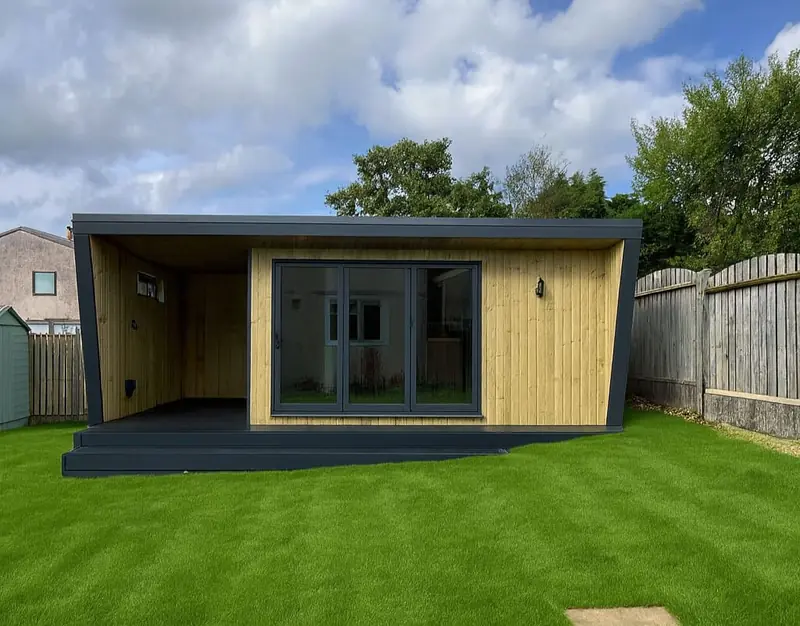 Garden room with an integrated covered seating deck, slatted timber cladding and anthracite bi-fold doors