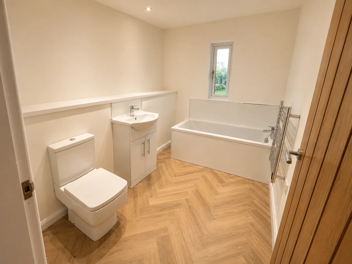 Bathroom in a garden annexe with a bath and shower screen, WC and basin unit over a herringbone floor
