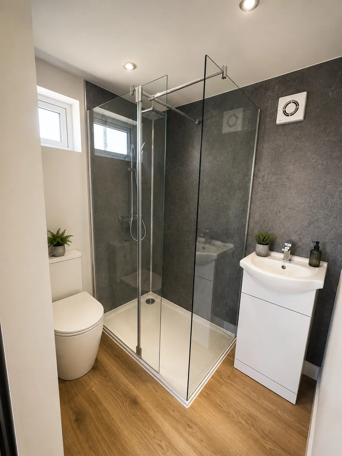 A tiled shower room in a garden annexe, walk-in glass screen, basin and WC